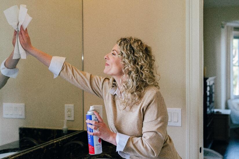 Woman cleaning custom glass mirror with spray bottle